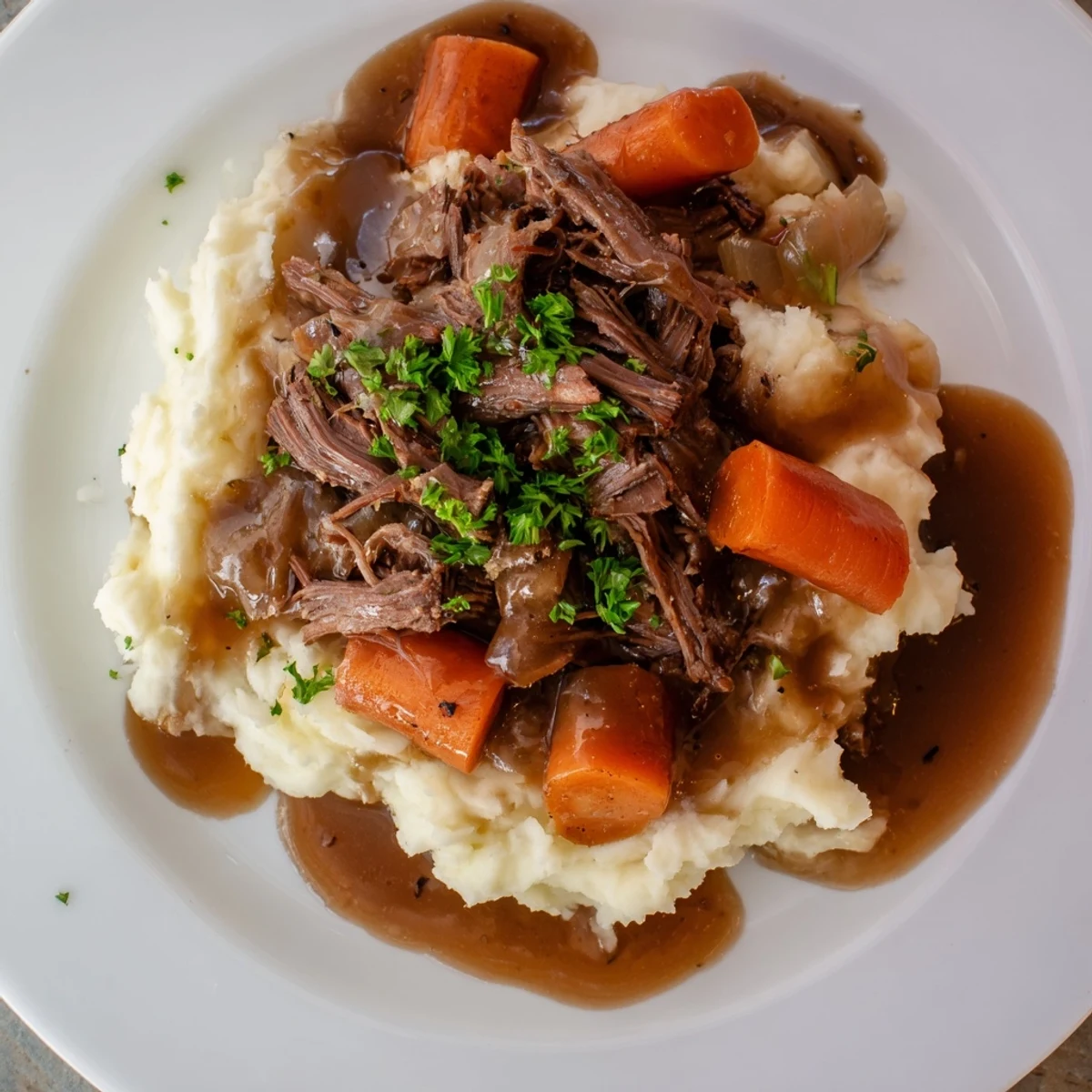 Tender Slow Cooker Pot Roast with rich gravy, carrots, plus creamy mashed potatoes ready to serve.