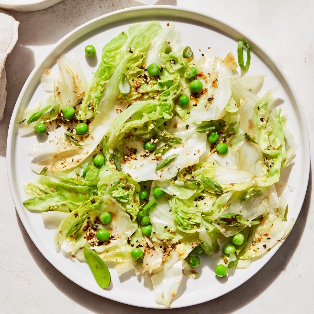 Steaming cabbage stir-fry with garlic and peas, coated in a glossy soy sauce, ready to serve.