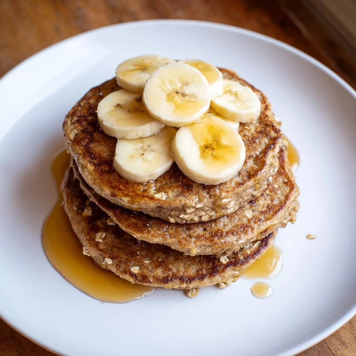 Freshly cooked banana oat pancakes, featuring a rustic texture and served with sliced bananas and berries.