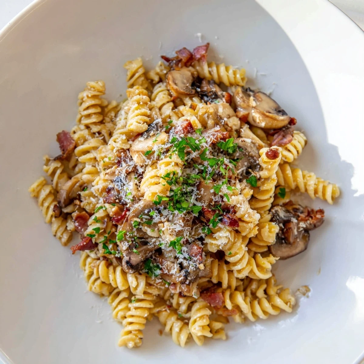 A comforting bowl of fusilli with bacon, onions, and mushrooms, steaming hot, ready to enjoy.