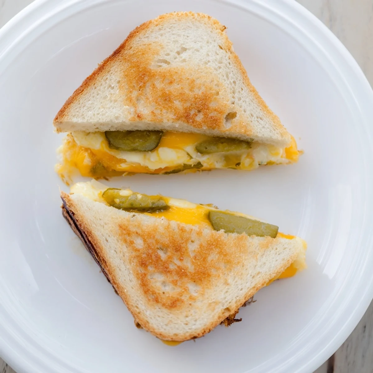 Crispy sourdough encases a warm, creamy Gooey Pickle Grilled Cheese, ready for dipping in tomato soup.