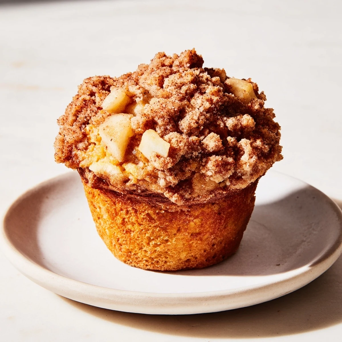 Golden-brown tasty apple muffins with a generous, buttery crumb topping just out of the oven.
