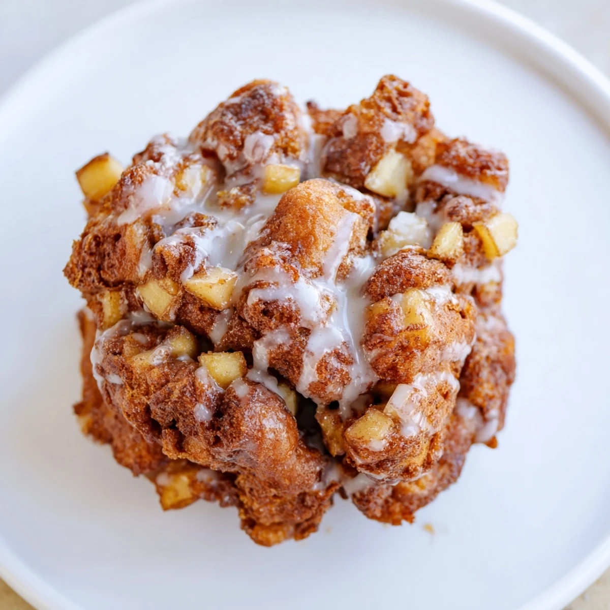Golden-brown homemade apple fritters, crispy outside, served warm with a sweet vanilla glaze.