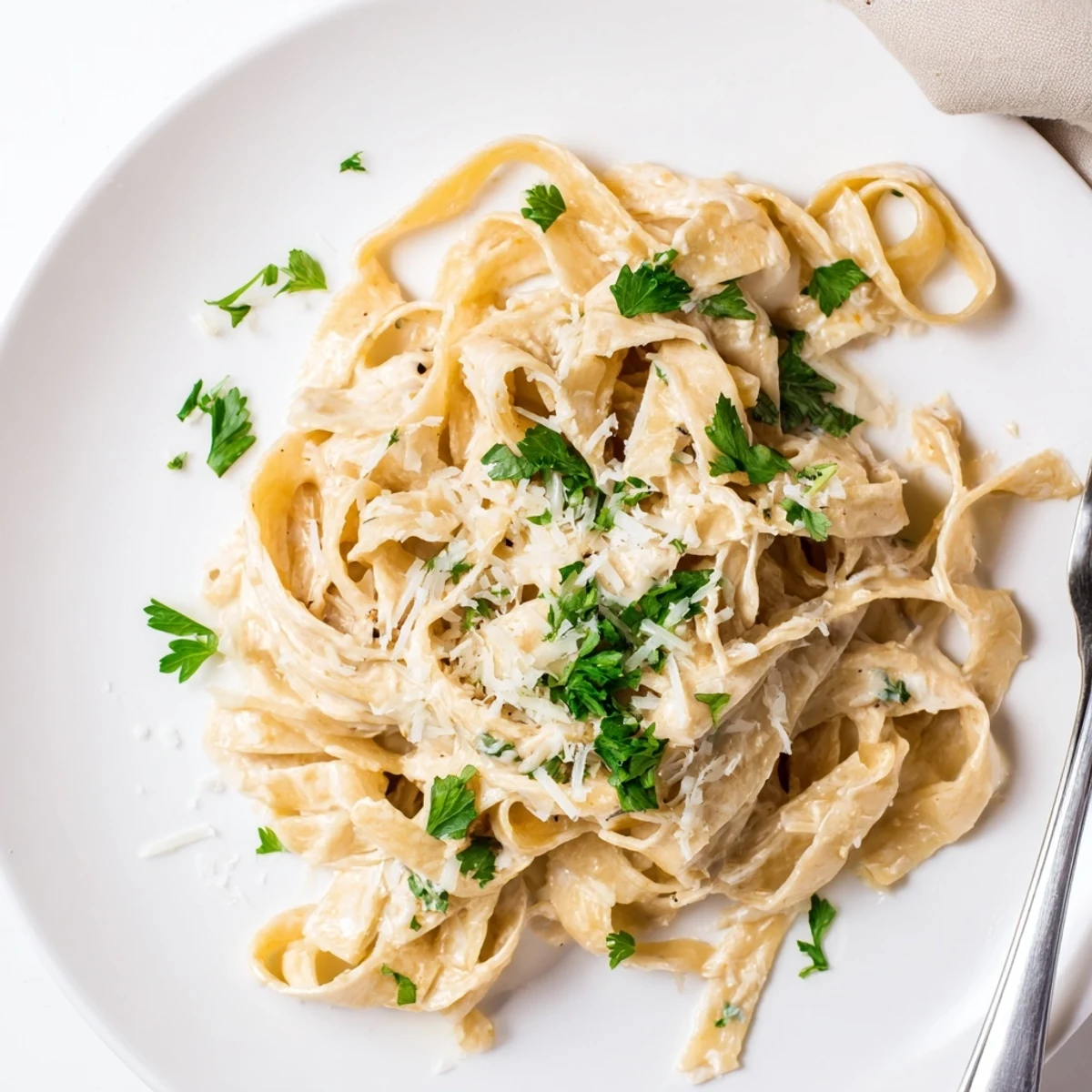 A bowl of Skinny Alfredo pasta, glistening with savory sauce, ready for a delicious meal.