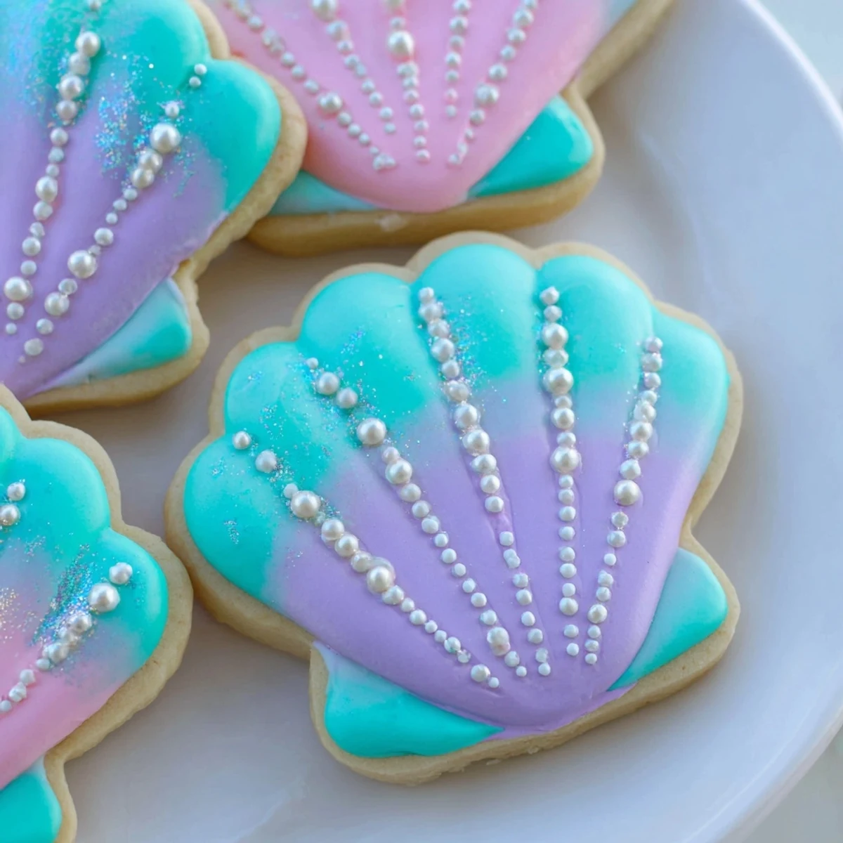 Delicate seashell sweets, pastel-colored sugar cookies perfectly crafted for a mermaid celebration, ready to eat.