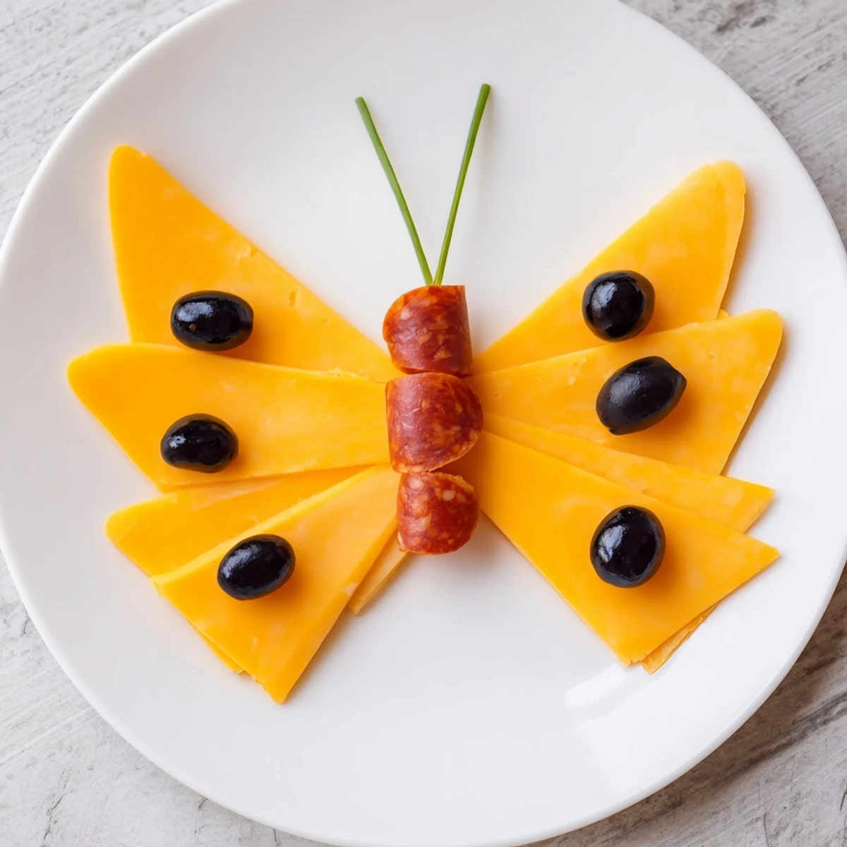 A party-ready butterfly migration appetizer platter with colorful cheddar wings, black olives, and salami.
