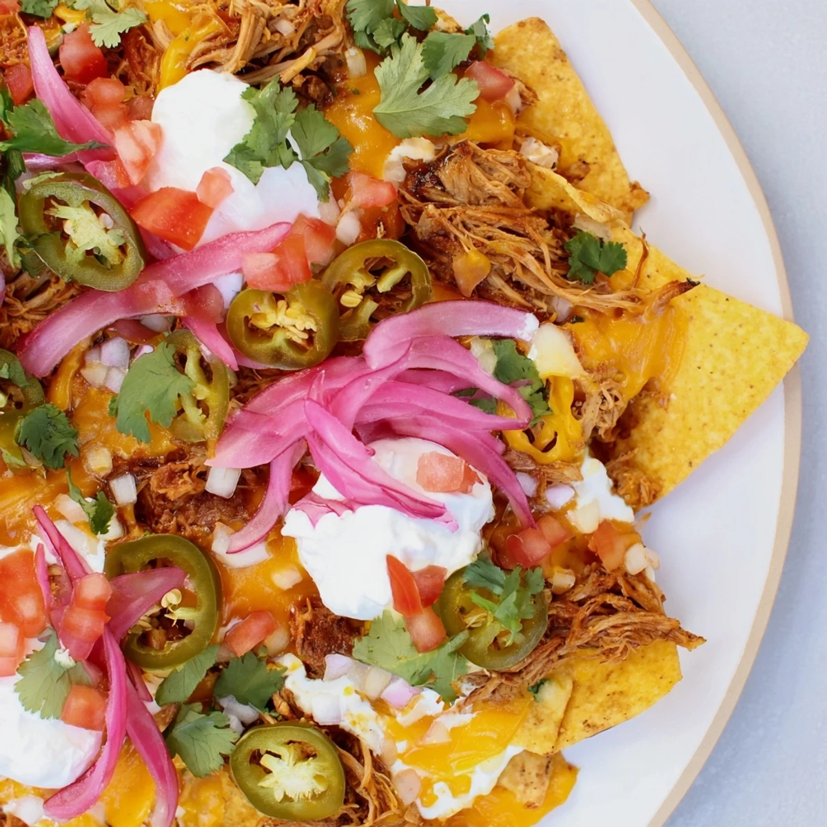 Golden, baked loaded nachos with pulled pork, featuring melty queso, spicy jalapeños, and fresh toppings.