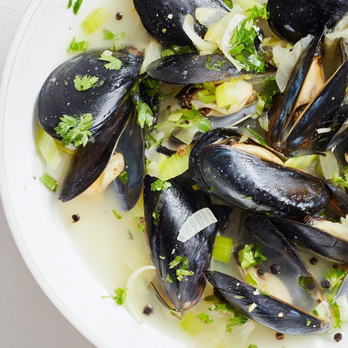 Steaming Belgian Moules Marinière, plump mussels with garlic and herbs, in a bright, flavorful broth.