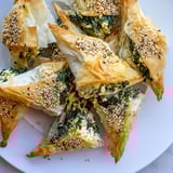 Golden, crispy Mini Spanakopita Triangle clusters reveal a cheesy, herb-filled spinach interior.