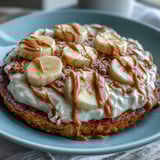 A slice of High-Protein Breakfast Pizza Bowl showing peanut butter drizzle and fresh banana slices.