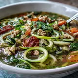 A steaming bowl of turkey and veggie zucchini noodle soup, filled with tender turkey, fresh spiralized zucchini, and colorful vegetables in a savory broth.