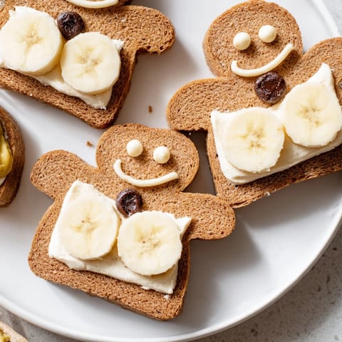 Gingerbread man sandwich cutouts with bright apple and raisin decorations, ready to eat.