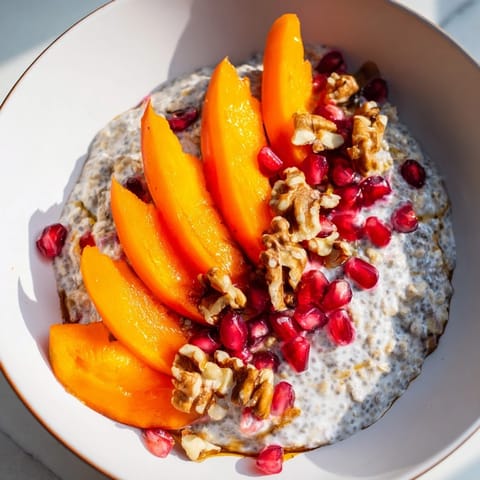 Freshly sliced persimmon tops a jar of overnight oats, studded with vibrant pomegranate seeds.