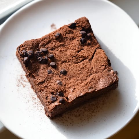 A warm, gooey slice of sweet potato brownie, drizzled with chocolate, ready to be enjoyed.