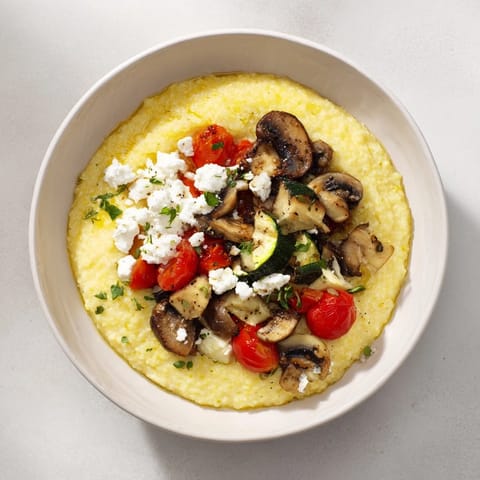 A close-up of a warm, comforting cornmeal mush polenta bowl with fresh herbs and a fried egg.