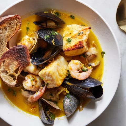 Golden-yellow bouillabaisse, a Provençal fish stew with toasted bread and vibrant rouille.