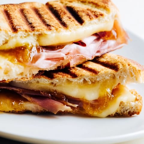 A close-up of the Crispy Prosciutto & Fig Panini with crispy bread and savory prosciutto slices.