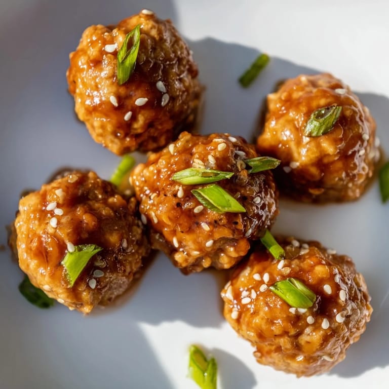 Close-up of Spicy Honey-Glazed Chicken Meatballs: tender, juicy bites coated in a sweet, spicy sauce.